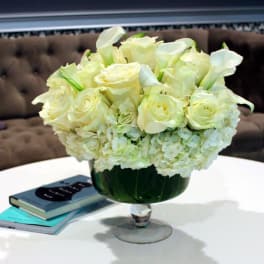 White roses and calla lilies arranged in a glass vase