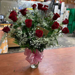 Bouquet of red roses and baby's breath in a glass vase with a pink ribbon