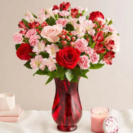 Bouquet of red and pink flowers in a red glass vase