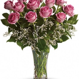 Pink roses arranged in a clear glass vase with white filler flowers