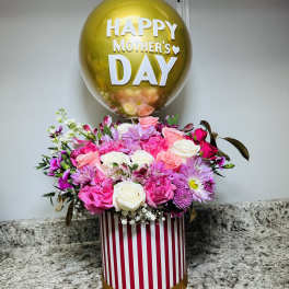 Pink and white flower arrangement with a gold Mother's Day balloon