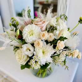 Round glass vase of white and blush flowers in a soft, airy arrangement