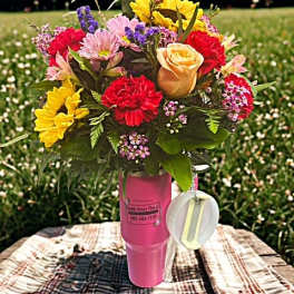 Mixed bouquet in a pink cup-style vase with a hanging tag
