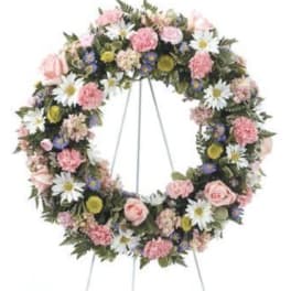Circular floral wreath on a stand with pink and white flowers