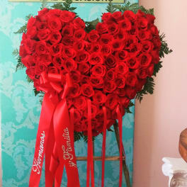 Heart-shaped arrangement of red roses with red ribbons