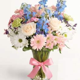 Mixed pastel bouquet in a clear glass vase with a pink ribbon