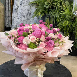 Large pink rose bouquet wrapped in pale pink paper with a ribbon