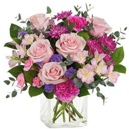 Pink roses and mixed blooms in a clear glass vase
