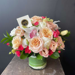 Peach and pink rose bouquet in a green glass vase