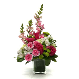 Pink roses and carnations in a clear glass vase with tall pink snapdragons