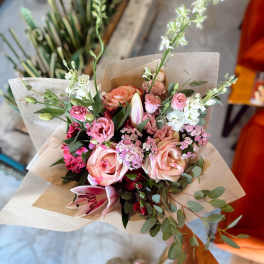 Hand-tied bouquet of pink and white flowers wrapped in paper