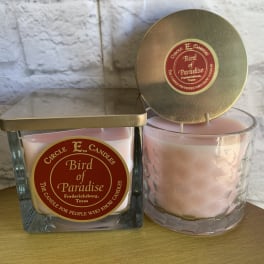 Two pink candles in glass containers with gold lids