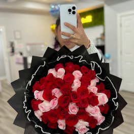 Large bouquet of red and pink roses wrapped in black paper