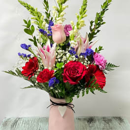 Mixed bouquet of red, pink, and white flowers in a pink vase