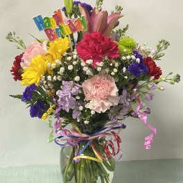 Colorful birthday bouquet in a glass vase with a "Happy Birthday" topper