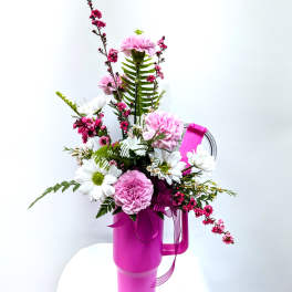 Pink and white flower arrangement in a bright magenta tumbler with ribbon