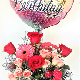Birthday balloon above a rose bouquet in a glass vase