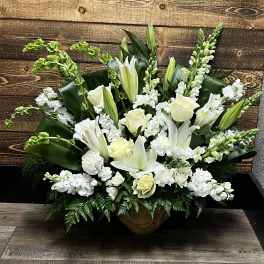 White lilies and roses arranged in a low urn with greenery