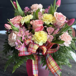 Pink and yellow bouquet in a magenta vase with plaid ribbon