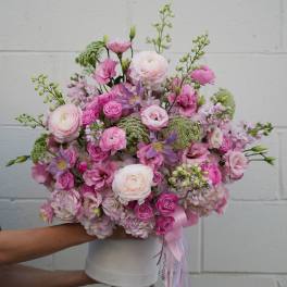 Pink and white mixed flower bouquet in a white vase with ribbon