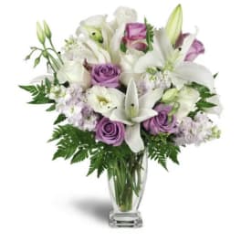 Bouquet of white lilies and lavender roses in a clear glass vase