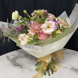Pastel bouquet with pink and white blooms wrapped in pale paper