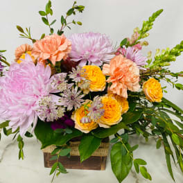 Mixed bouquet of pink, peach, and yellow flowers in a wooden box