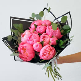 Bouquet of bright pink peonies with eucalyptus in black wrap