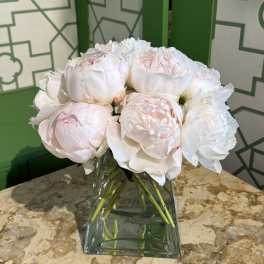 White and pale pink peonies arranged in a clear glass vase