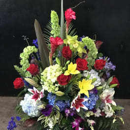 Large standing floral arrangement with red roses, lilies, and hydrangeas