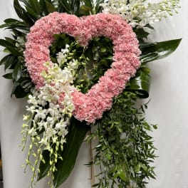 Heart-shaped pink carnation wreath with white orchids and greenery