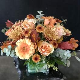 Peach and orange bouquet in a square glass vase