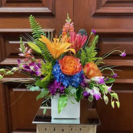 Colorful mixed flower arrangement in a white square vase