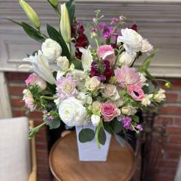 Mixed pink and white flower arrangement in a white vase