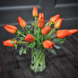 Orange tulips arranged in a clear glass vase