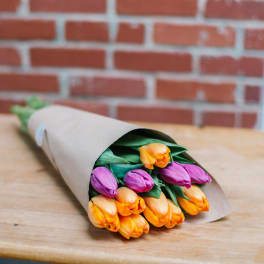 Bouquet of orange and purple tulips wrapped in brown paper