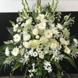 Large white floral arrangement in a black pedestal vase