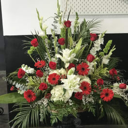 Large red and white floral arrangement in a black pedestal vase