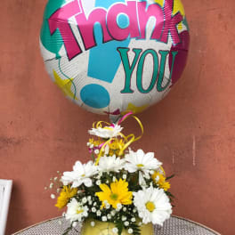 Daisy bouquet in a smiley-face vase with a colorful thank-you balloon
