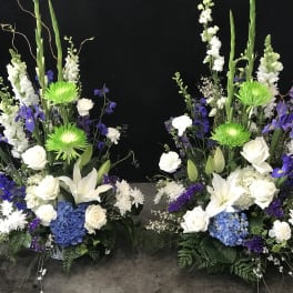 Two tall floral arrangements with white, blue, and purple blooms