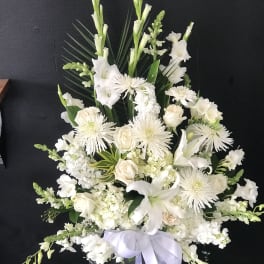 White floral arrangement in a dark vase with a lavender ribbon