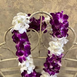 Purple and white orchid leis draped over a metal chair