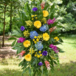 Tall standing floral spray with yellow, blue, purple, and pink blooms