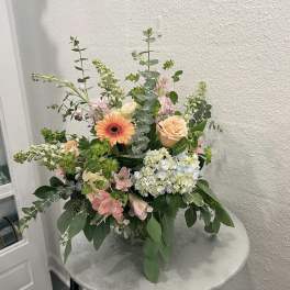 Mixed floral arrangement with peach roses, gerbera daisy, and hydrangea in a vase