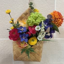 Colorful mixed bouquet in a woven basket with bright blooms