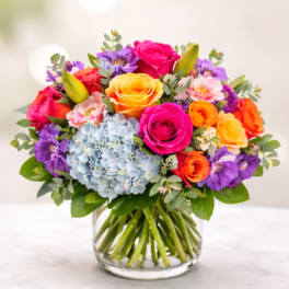 Colorful bouquet of roses, hydrangea, and lilies in a glass vase