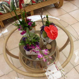 Three tropical floral arrangements on a glass table