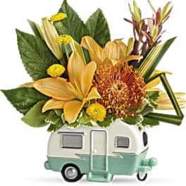 Yellow and orange floral arrangement in a camper-shaped container