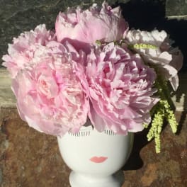 Pink peonies arranged in a white face-shaped vase