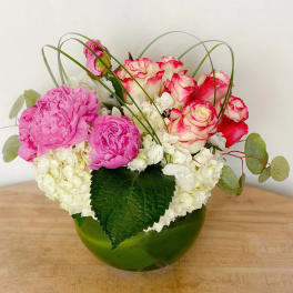Pink and white roses with white hydrangeas in a green glass bowl